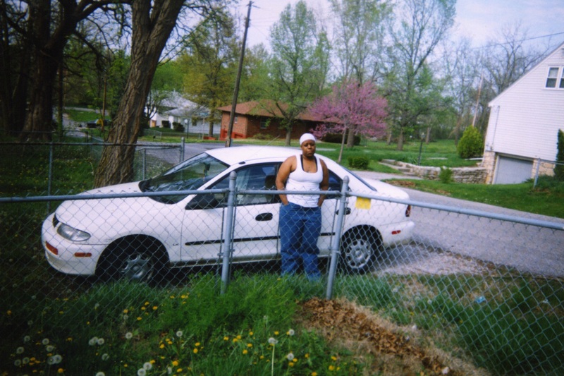 Starla Carr stands in front of a white sedan.