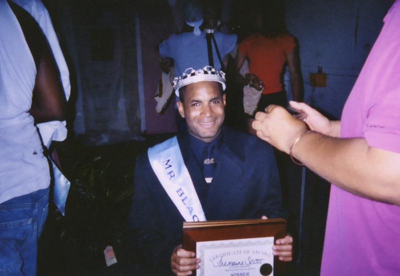A contestant at Soakie's "Mr. and Miss Black Gay Pride 2003" grins while holding a plaque.  