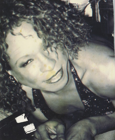 Tisha Taylor smiles in a close-up photo. She is wearing a sparkly top with a plunging neckline. 